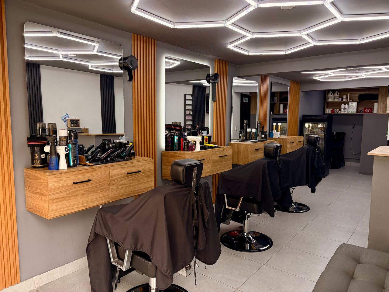 Interior de barbería con luz tibia, silla clásica y espejo enmarcado